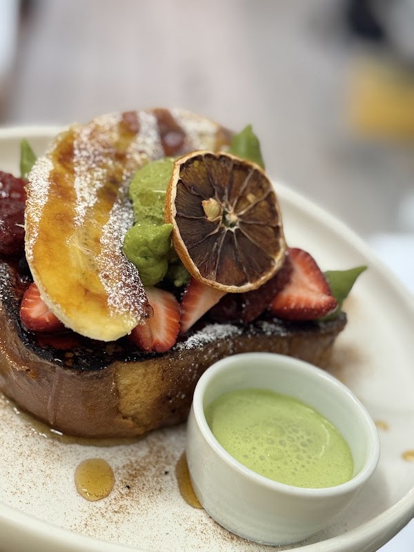 Matcha French toast topped with fruit, served with a matcha accompaniment